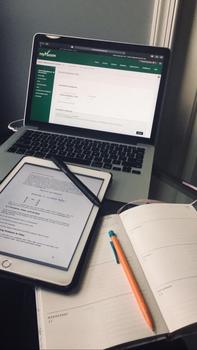 A Macbook open to Mason Blackboard page, a kindle, and a notebook with a pencil on a desk.