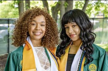 Image of graduating seniors Ashley and Briana Dawson standing side by side in their graduation regalia