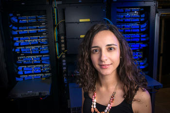 Foteini Baldimtsi standing in front of computers.