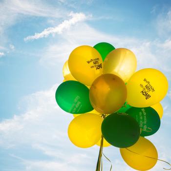 Green and gold balloons against a bright blue sky