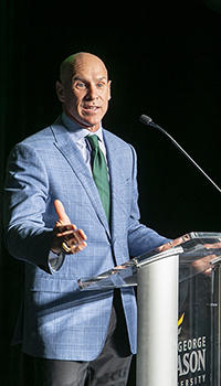 Brad Edwards in a grey sportcoat and green tie at a podium