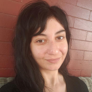 PhD student Ioanna Karantaidou sits in front of a brick wall for her news profile.