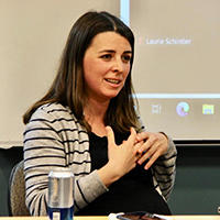A woman in a gray and black striped sweater is in conversation.