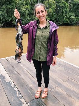 Tovah Siegel by the water and holding fish.