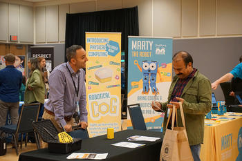 Vendors and symposium attendees talk in an expo hall